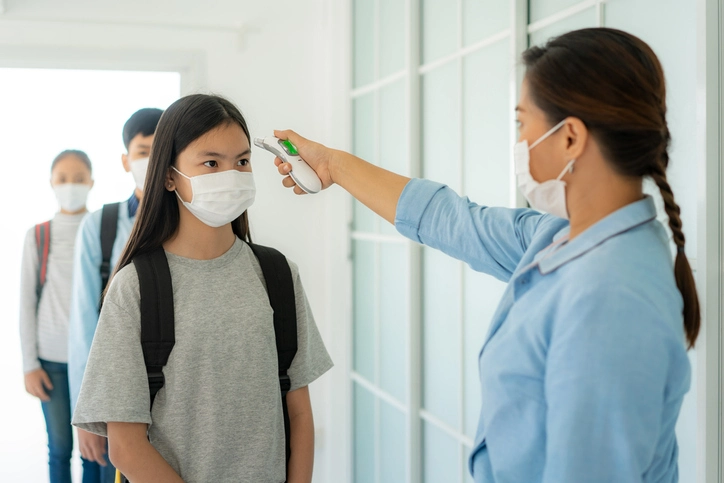 child being tested for a fever while going back to school