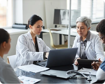 Medical professionals gathered around in a meeting, discussing patient care.