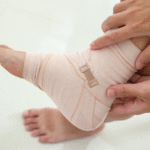 A man holding his sprained ankle with a white bandage on