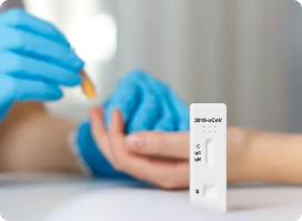 Gloved hands performing a finger-prick blood test on a patient.