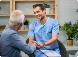 Smiling male nurse or doctor shaking hands with an elderly male patient.