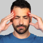 A man is holding his head in pain, indicating he is suffering from a headache.