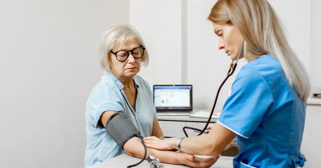 Nurse measuring blood pressure of elderly woman in clinic.