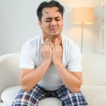 Man clutching throat, acid reflux causing breathing problems.