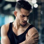 Man gripping his shoulder in discomfort from muscle ache.