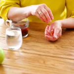 Person preparing to take medication with water and tea for fast diarrhea relief.