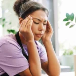 Woman holding head in pain while experiencing a headache.