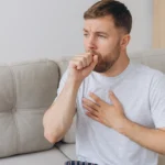 Man coughing and holding chest, showing common shortness-of-breath triggers.