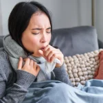 Woman coughing heavily at home while feeling unwell